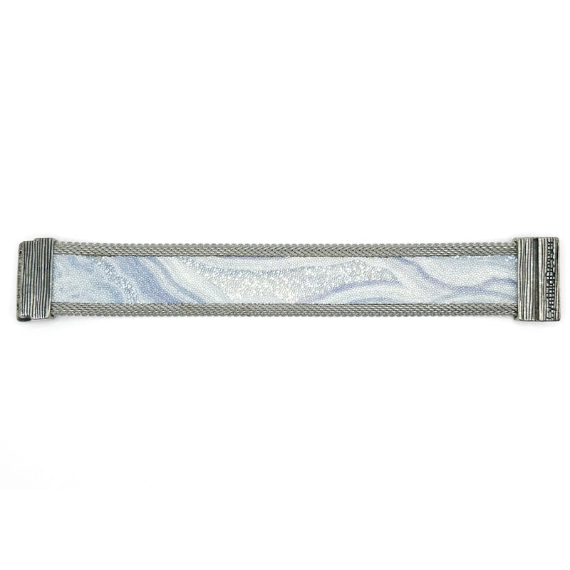 Narrow cuff bracelet with blue lace agate slice pattern highlighted by shiny and matte Swarovski micro-crystals, with matte silver mesh edges, laid open flat to show the signature Cynthia Desser magnetic clasp, on a white background.