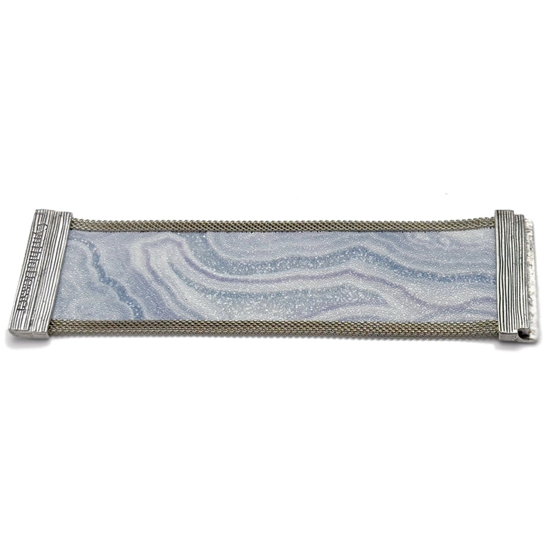 Wide cuff bracelet with blue lace agate slice pattern highlighted by shiny and matte Swarovski micro-crystals, with silver mesh edges, laid open flat to show off the signature Cynthia Desser magnetic clasps, on a white background.
