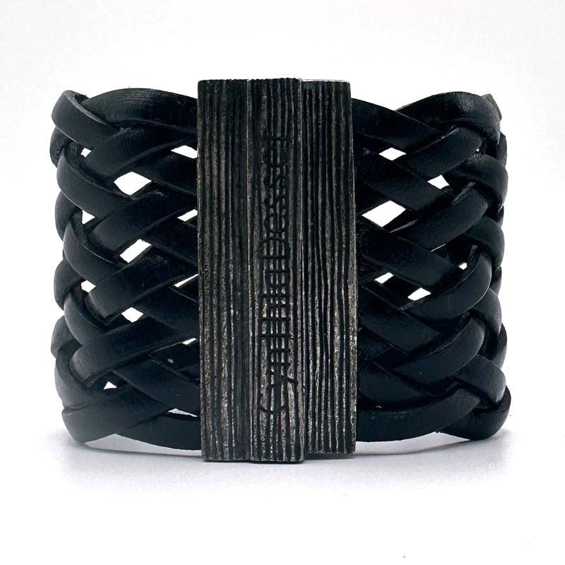 Back view of a wide cuff bracelet of braided black Italian leather, closed with the signature gunmetal Cynthia Desser magnetic clasp.