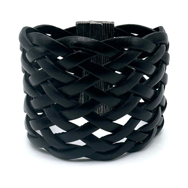 Wide cuff bracelet of braided black Italian leather, tilted show the closed gunmetal magnetic clasp.