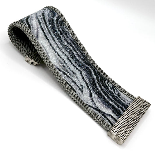 Wide cuff bracelet with black and white agate slice pattern highlighted by shiny and matte Swarovski micro-crystals, with matte silver mesh edges, open with one end curled under to show off the signature Cynthia Desser magnetic clasp, on a white background.
