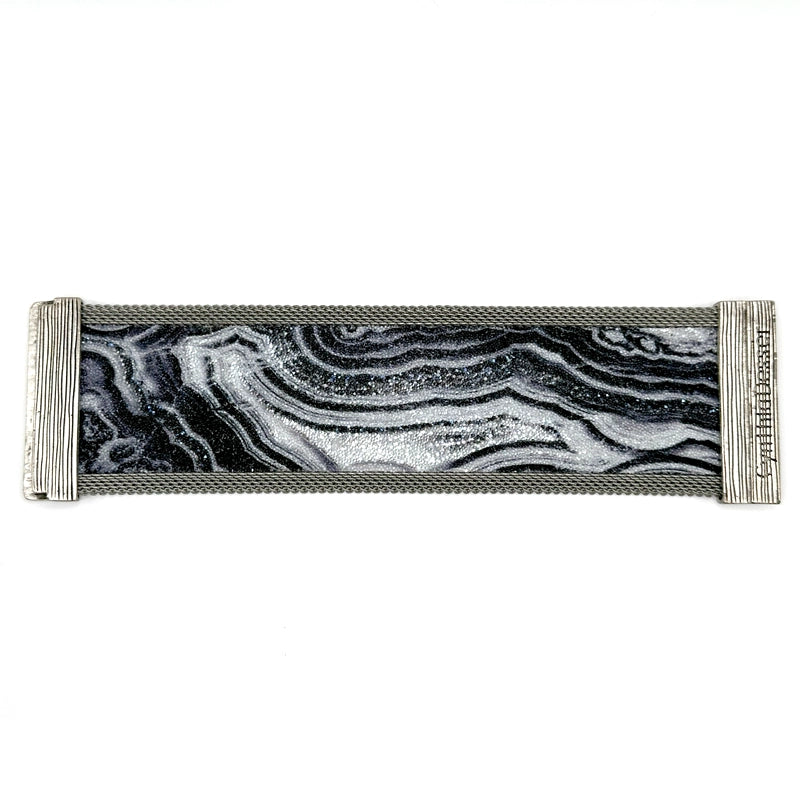 Wide cuff bracelet with black and white agate slice pattern highlighted by shiny and matte Swarovski micro-crystals, with matte silver mesh edges, laid open flat to show off the signature Cynthia Desser magnetic clasps, on a white background.