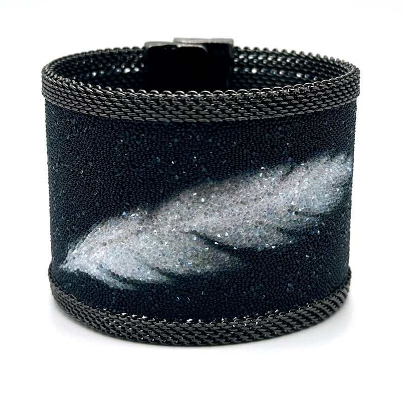 Wide cuff bracelet with matte black Swarovski micro-crystals surrounding a shimmery white crystal feather image, with gunmetal mesh edges, tilted to show the closed magnetic clasp, on a white background.